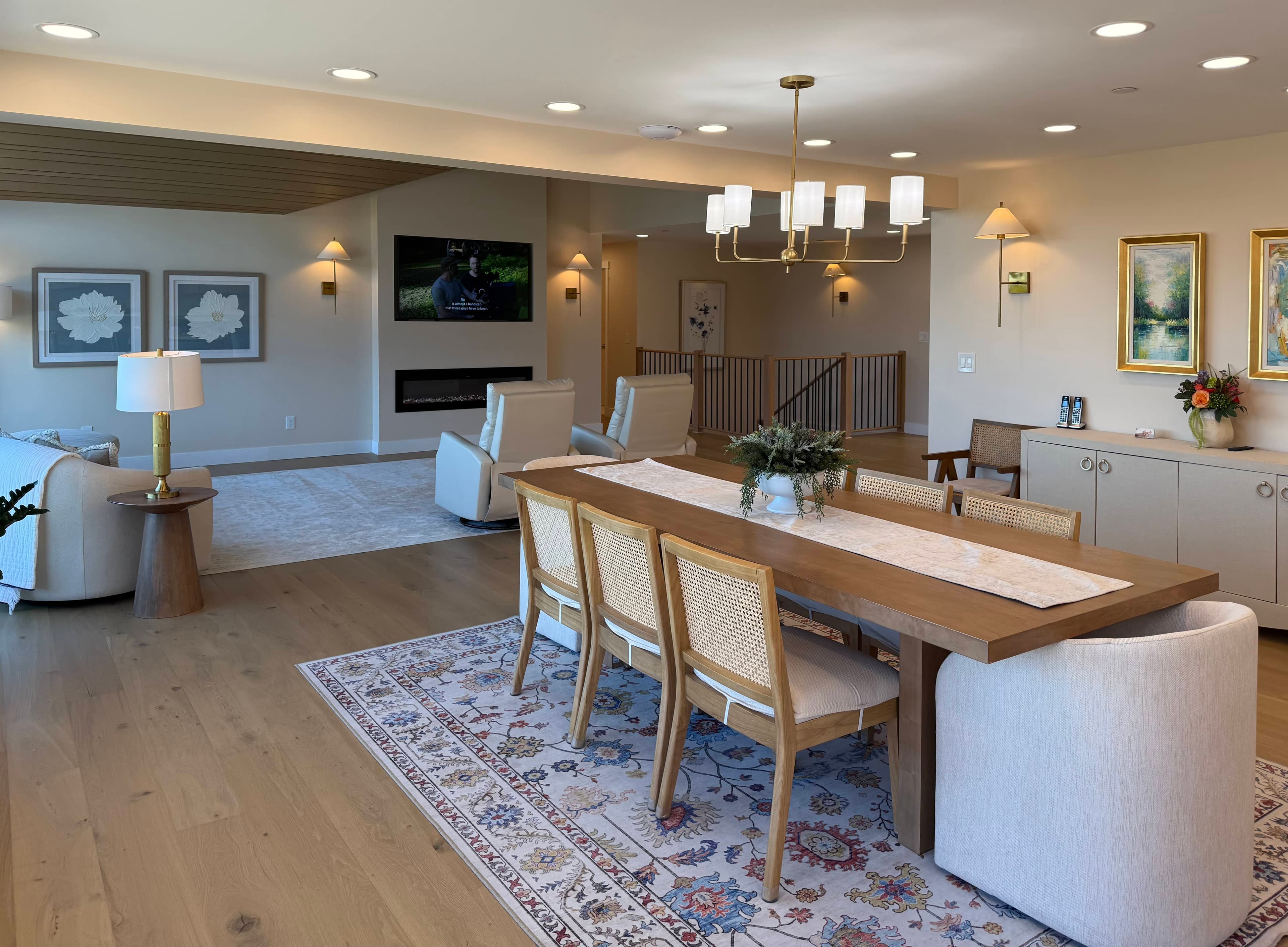 Open-plan dining and living area with a wood dining table and surrounding chairs.