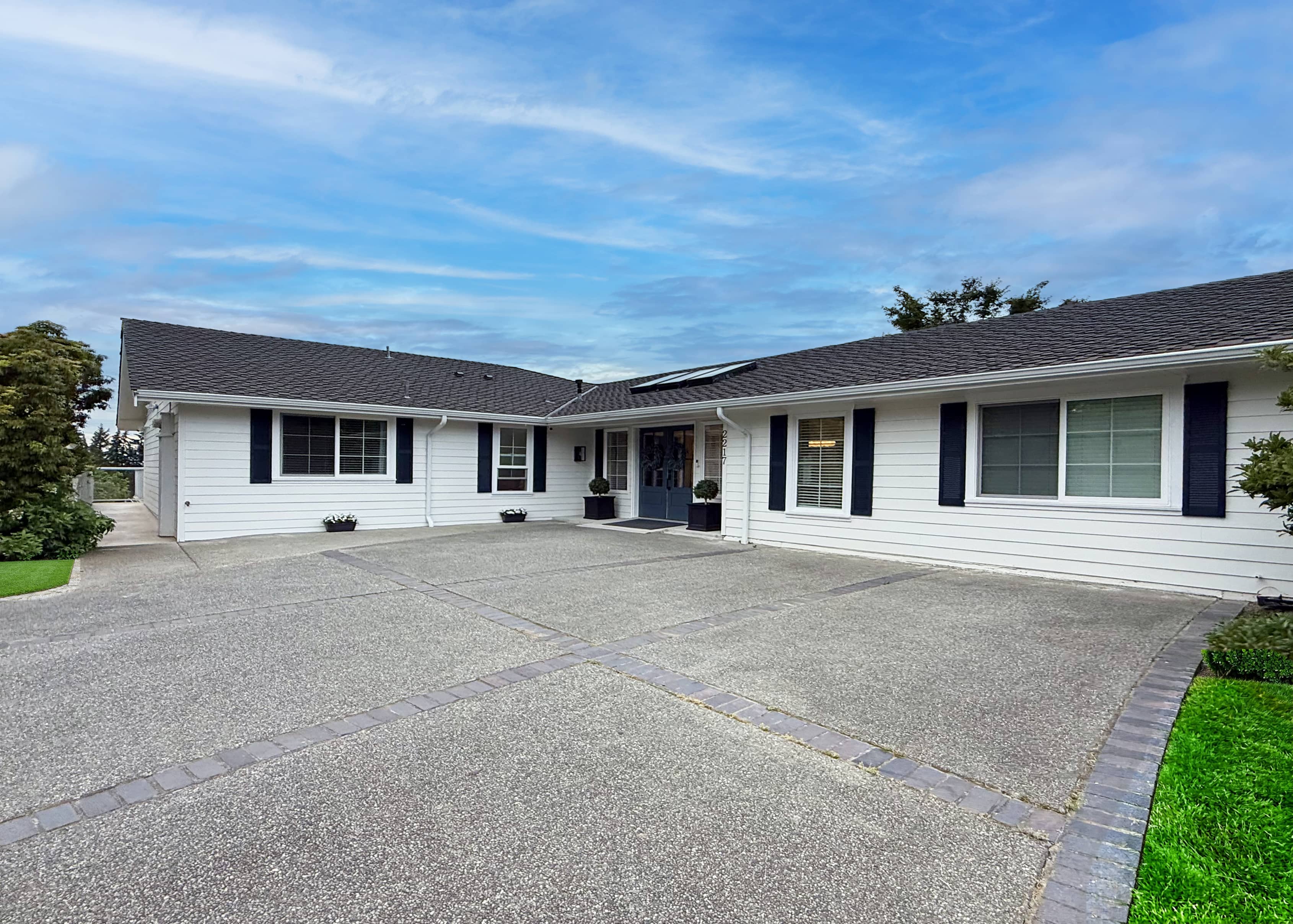 Front exterior of Norwood House with neutral siding and trimmed shrubs.