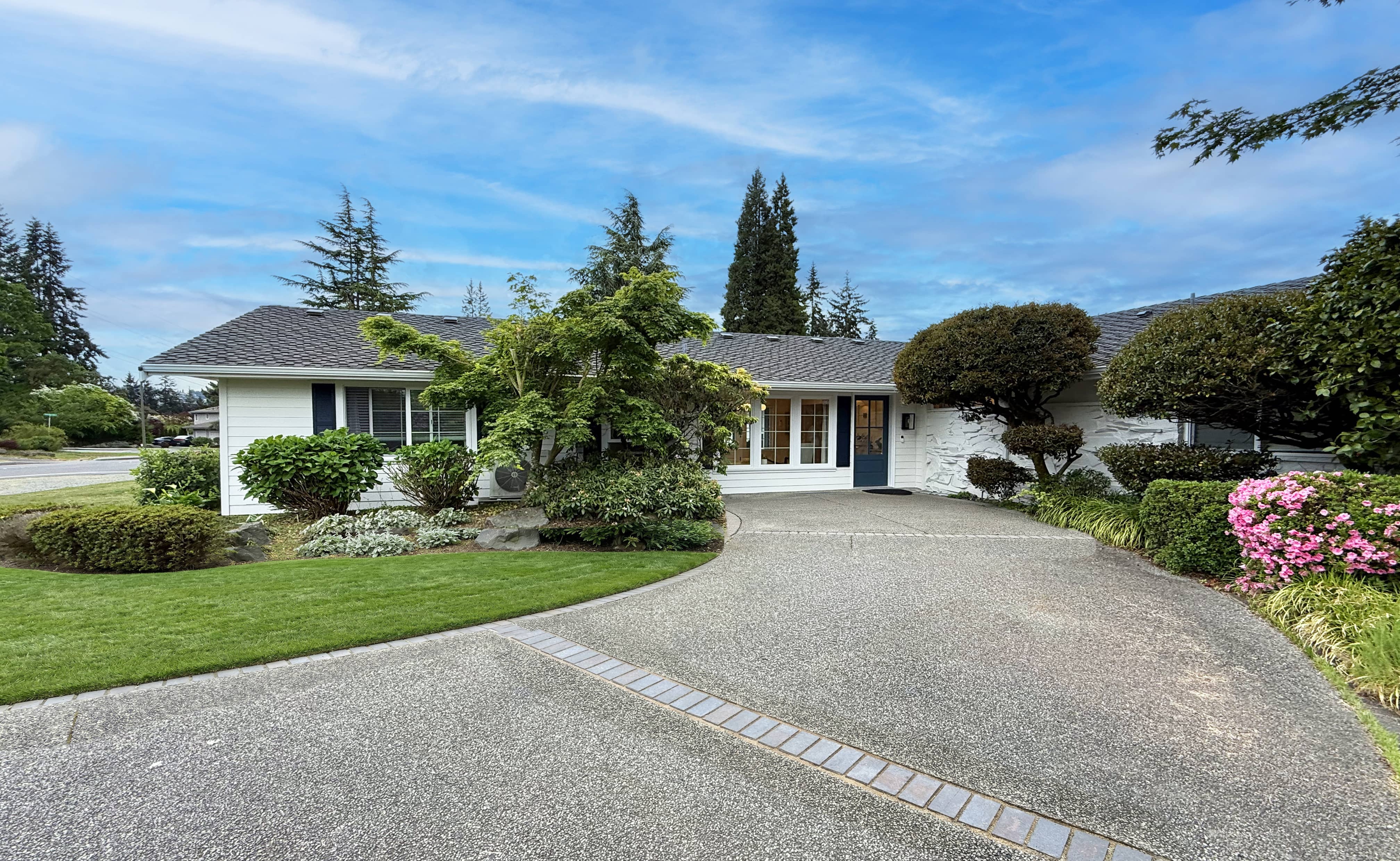 Wide view of Norwood House from across the street, mature landscaping and a long driveway.