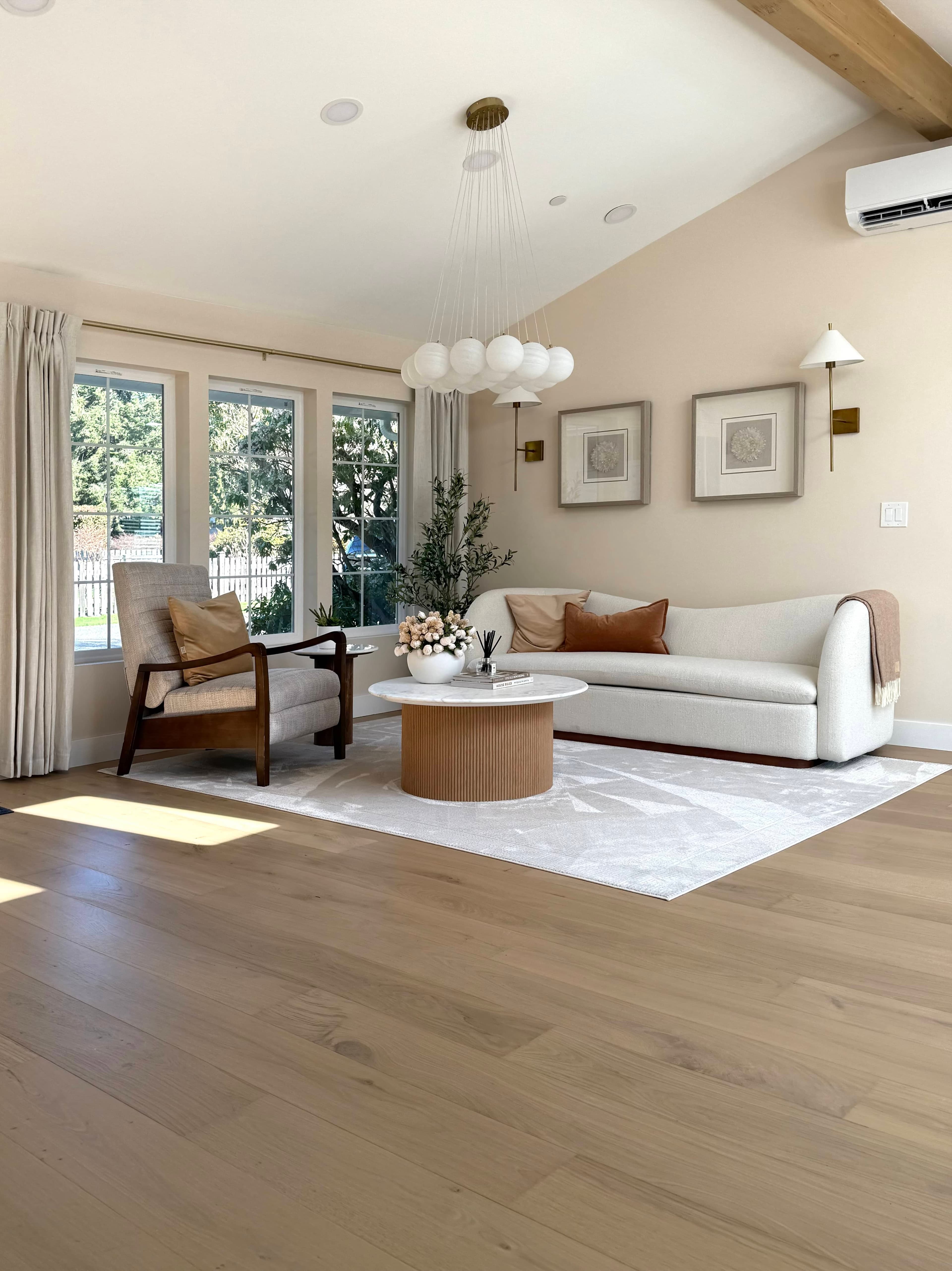 Norwood House living room: a cream sectional sofa, wood floors, layered rugs, and a chandelier overhead.